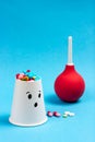 Patient with pills - colored medical pills on a blue background. In the background is a medical enema. The theme of the