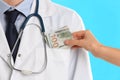 Patient putting bribe into doctor`s pocket on blue background, closeup. Corruption in medicine Royalty Free Stock Photo