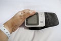 Patient`s hand holding digital tensiometer on hospital bed