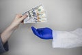 Patients hand holds out money to the doctor. The concept of corruption in healthcare, bribery or paid medicine