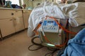 A patient seen in a hospital bed with tubes attached to a bed adjustment machine.