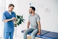 Patient sitting on couch and doctor writing prescription on clipboard in massage cabinet at clinic