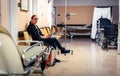 Patient sitting in hospital ward hallway waiting room with iv. Royalty Free Stock Photo