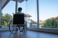 The patient sitting on a wheelchair that cannot help himself is staring out of the glass room hopelessly Royalty Free Stock Photo