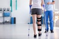 Patient with stiffener on the leg walking with crutches