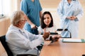 Patient in wheelchair discuss her health with doctor in sterile room.