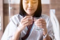 Patient woman hands holding pills and a glass of water at hospital Royalty Free Stock Photo