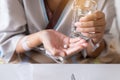 Patient woman hands holding pills and a glass of water at hospital Royalty Free Stock Photo