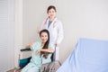 Patient woman is sitting in a wheelchair with doctor standing behind smiling and thumbs up together at hospital Royalty Free Stock Photo