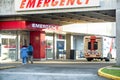 Patients go to the hospital to an emergency entrance, an ambulance and paramedics car stand nearby