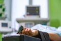 Patients hand with a sensor on the blurry background of the group of doctors in the operating room. Close up, Selective Royalty Free Stock Photo