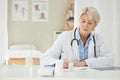 Patients need their medication. a mature doctor filling out prescriptions in her office. Royalty Free Stock Photo