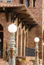 Patina green and rust white globe lampposts in front of row of orange brick arches