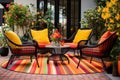 a patio with outdoor wicker chairs and colorful rug