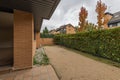 Patio of a semi-detached house with brown stoneware floors and sandy terrain with a bushy hedge separating it from the neighbors Royalty Free Stock Photo