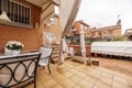 Patio of a semi-detached house with brown stoneware floors, stairs of the same material with white metal railings and awnings and