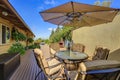 Patio table set with opened umbrella. Wooden walkout deck Royalty Free Stock Photo