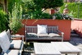 Patio tucked away in a beautiful garden corner with red-painted walls, flowering plants and cozy benches with cushions. Royalty Free Stock Photo