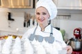 Patissier in her bakery shop with lots of meringue