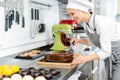 Patissier pouring liquid chocolate on a cake