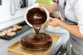 Patissier pouring liquid chocolate on a cake