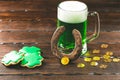 Patrick`s day background with a Glass of green beer and clover gingerbread with gold coins on wooden Royalty Free Stock Photo