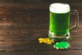 Patrick`s day background with a Glass of green beer and clover gingerbread with gold coins on wooden