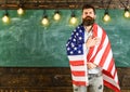 Patriotic education concept. American teacher covered with american flag. Man with beard and mustache on serious face Royalty Free Stock Photo