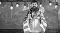 Patriotic education concept. Man with beard and mustache on happy face holds flags of USA, in classroom, chalkboard on