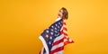 Happy child, cute girl with American flag on yellow studio background. USA celebrate July 4th, independence Day.