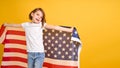 Happy child, cute girl with American flag on yellow studio background. USA celebrate July 4th, independence Day.