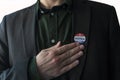 Patriotic man with usa I Voted sticker in his suit touching hand on his chest