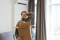 Patriotic military man in uniform keeps box in new apartments. Buying a property Royalty Free Stock Photo