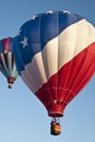 Patriotic red white and blue hot-air balloon taking off with many other hot air balloons into the blue morning sky Royalty Free Stock Photo