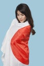 Patriotic young woman wrapped in Japanese flag over blue background