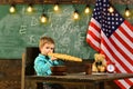 Patriotism and freedom. Little boy eat bread at American flag at knowledge day. School kid at lesson in 4th of july Royalty Free Stock Photo