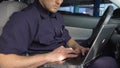 Patrolman using laptop to check road situation in city, online criminal database