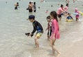 People sunbathe and swim.Some vacationers stroll along the shore