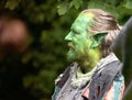 Portrait of a middle-aged man attending a public fantasy festival dressed as an elf with green colored skin and pointed ears