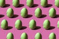 Patter with green quail eggs on pink background, strong light shadows. Easter design