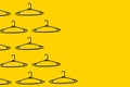 Pattern of black plastic hangers on a yellow background with copy space. The concept of selling goods, shopping and retail.