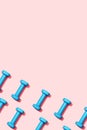 Pattern blue dumbbells on a pink background top view. Fitness gymnastic equipment for female home workouts and exercises. An