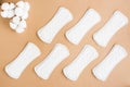 A pattern of clean disposable sanitary pads and a branch of cotton on a beige background. Women`s health and comfort concept. Top Royalty Free Stock Photo