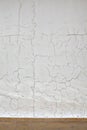 Pattern of cracks on the white plaster coated wall, textured background