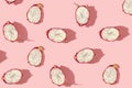 Pattern created from fresh exotic dragon fruits halfs on pastel pink background. Top view