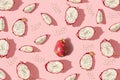 Pattern created from fresh exotic dragon fruits whole, halfs and seeds on pastel pink background. Top view