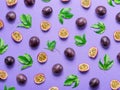 Pattern of dark purple passion fruits, it\'s halves and leaves on light purple table Royalty Free Stock Photo