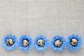 Pattern of decorated quail eggs in the form of blue flowers on a background of natural linen fabric. Children`s creativity, craft