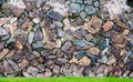 Pattern decorative uneven cracked real stone wall surface with cement and green grass Royalty Free Stock Photo