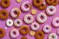 A pattern of donuts with different glazes, on a pink background.